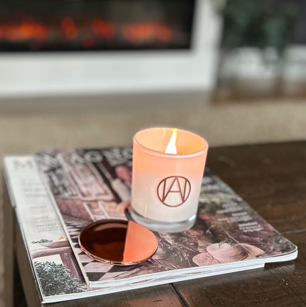 Candle with a logo on a magazine in front of a fireplace
